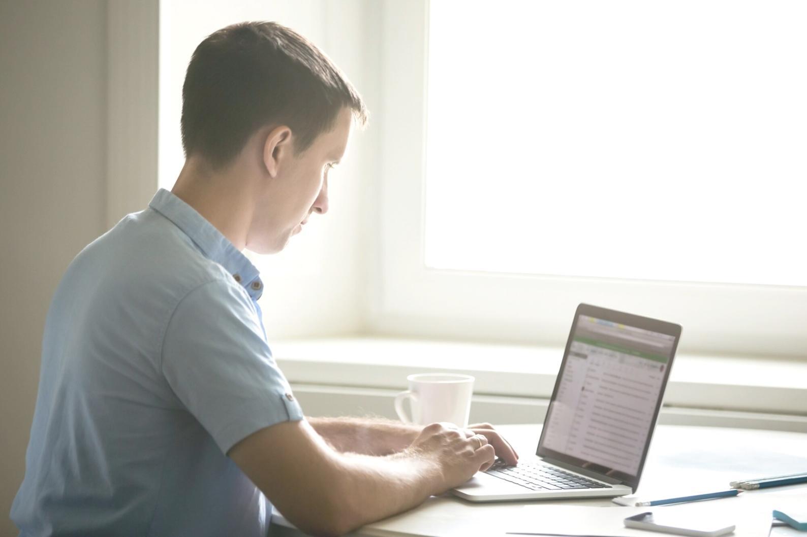 Persoană analizând rapoarte financiare pe laptop în biroul modern